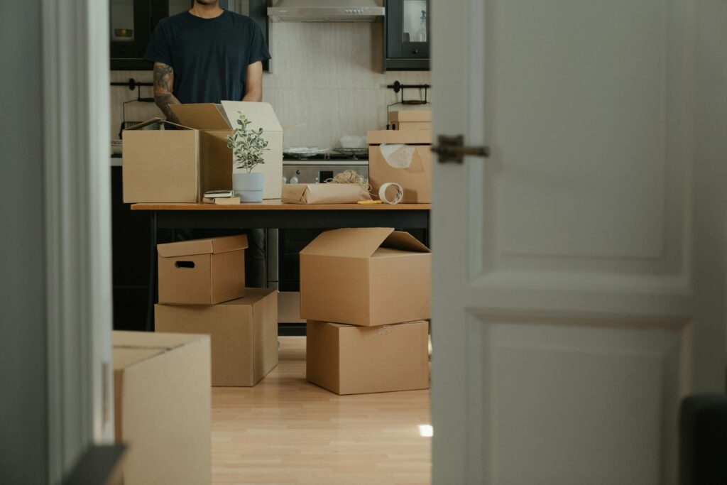 Person unpacking cardboard boxes in a modern kitchen during relocation.